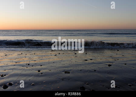 Wellen nähern sich bei Ebbe dem Meer und rotes Licht am Horizont, Sonnenuntergang an der Küste in cleveleys an der fylde-Küste in lancashire uk Stockfoto