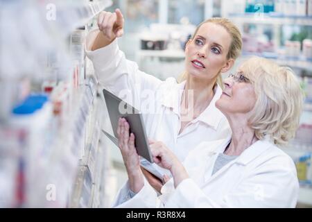 Weibliche Apotheker Kontrolle der Arzneimittel im Regal mit digitalen Tablet. Stockfoto