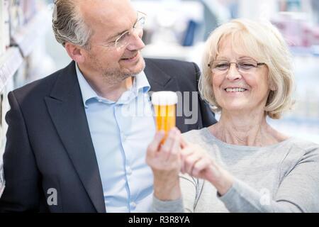 Lächelnde ältere Frau, Pille Etikett zu reifen Mann in der Apotheke. Stockfoto