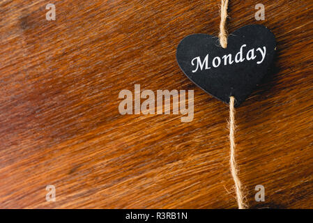 Herzen von schwarzem Holz mit Tag der Woche, am Montag. Stockfoto