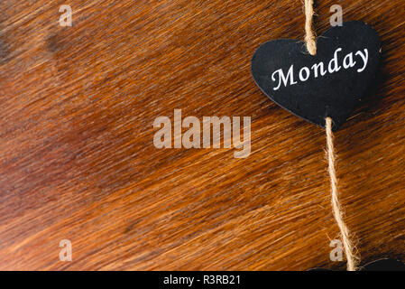 Herzen von schwarzem Holz mit Tag der Woche, am Montag. Stockfoto