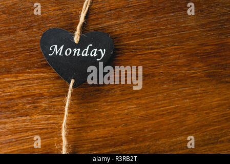 Herzen von schwarzem Holz mit Tag der Woche, am Montag. Stockfoto