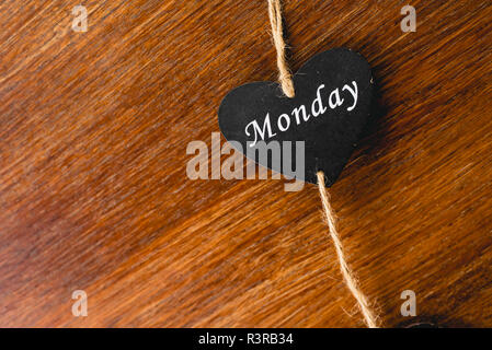 Herzen von schwarzem Holz mit Tag der Woche, am Montag. Stockfoto