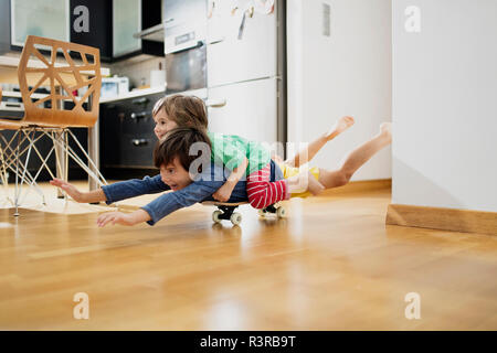 Zwei Brüder zu Hause liegen auf Skateboard zusammen Spaß haben Stockfoto