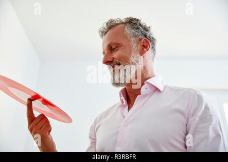 Lächelnd reifer Mann mit roten Vinyl record Stockfoto