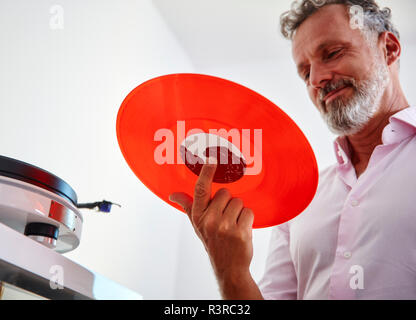 Lächelnd reifer Mann mit roten Vinyl record Stockfoto