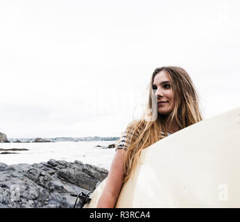 Junge Frau am Strand Surfbrett, Porträt Stockfoto