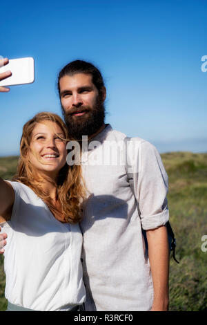 Junges Paar, Smartphone selfies am Strand Stockfoto