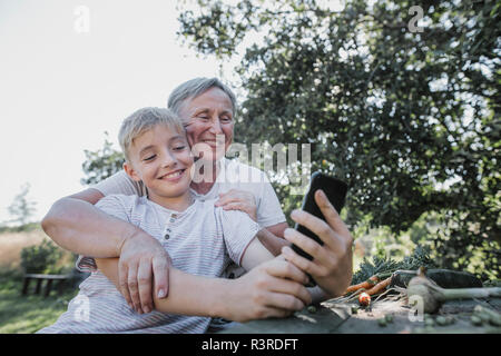 Gerne Großmutter und Enkel eine selfie im Garten Stockfoto