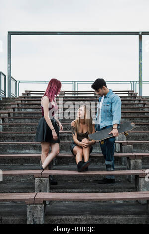 Freunde mit Skateboard entspannen auf zuschauertribünen Stockfoto