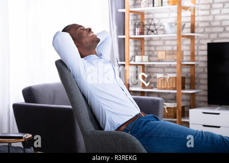 Seitenansicht eines jungen Mann auf Stuhl zu Hause Stockfoto