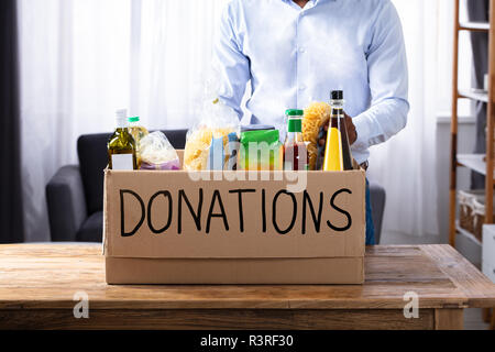 Mann mit verschiedenen Lebensmittel in Spendenbox Stockfoto