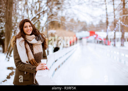 Junge Frau trinkt Tee oder Kaffee über Winter Natur Hintergrund im Freien Stockfoto