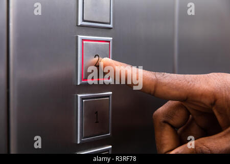 Close-up In eines Mannes Finger drücken auf der zweiten Etage Fahrstuhl Taste Stockfoto