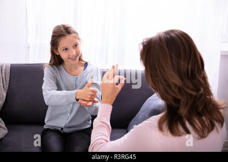Glückliches Mädchen sitzt auf einem Sofa lernen Sprachen von Frau Stockfoto