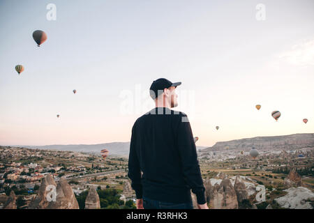 Ein Mann, der in der Einsamkeit bewundert einen schönen Blick auf das fliegende Ballons in Kappadokien in der Türkei. Stockfoto