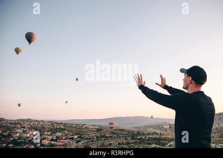 Ein Mann, der in der Einsamkeit bewundert einen schönen Blick auf das fliegende Ballons in Kappadokien in der Türkei. Stockfoto