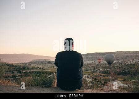 Ein Mann, der in der Einsamkeit bewundert einen schönen Blick auf das fliegende Ballons in Kappadokien in der Türkei. Stockfoto