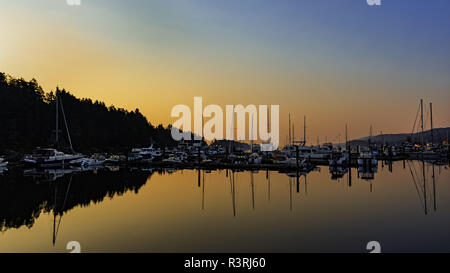 Eine orange Sunrise und Boote bei Ganges Hafen auf Salt Spring Island British Columbia Kanada wider Stockfoto