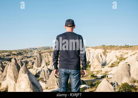 Ein Mann steht auf einem Berg in der Einsamkeit, bewundert die schöne Aussicht auf die Naturlandschaft in Kappadokien in der Türkei Stockfoto