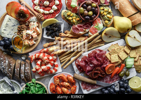 Italienische Antipasti Snacks. Brushettas, Käse Vielfalt, Garnelen, Lachs, Oliven, Schinken mit Birne, Salami und Schinken über Graues grunge Tabelle Stockfoto