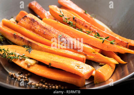 Gebratene Möhren mit Thymian, Koriandersamen und Honig in einem wok pfanne Rezept für Wurzelgemüse, ausgewählte konzentrieren, enge Tiefenschärfe Stockfoto