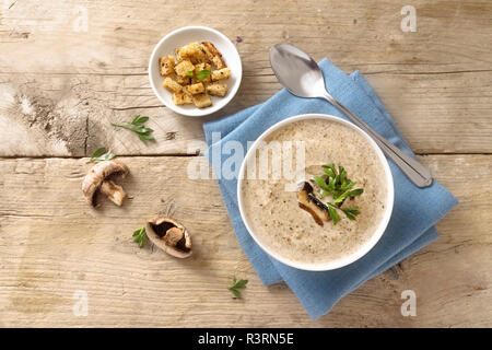 Pilz Cremesuppe mit Kraut garnieren und Croutons auf einem rustikalen Holztisch mit Kopie Raum, hohe Winkel, Ansicht von oben Stockfoto