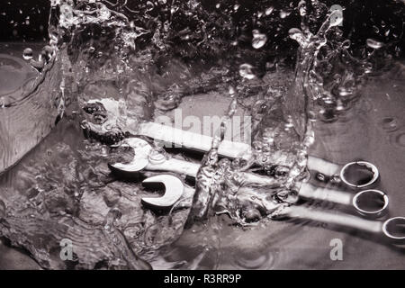 Schlüssel in verschiedenen Größen auf einem dunklen Hintergrund in eine Sprühflasche mit Wasser. Stockfoto