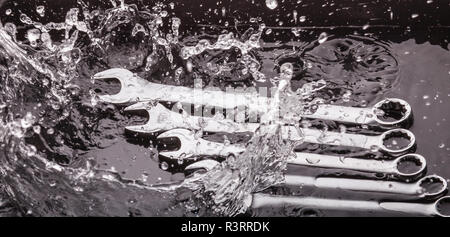 Schlüssel in verschiedenen Größen auf einem dunklen Hintergrund in eine Sprühflasche mit Wasser. Stockfoto