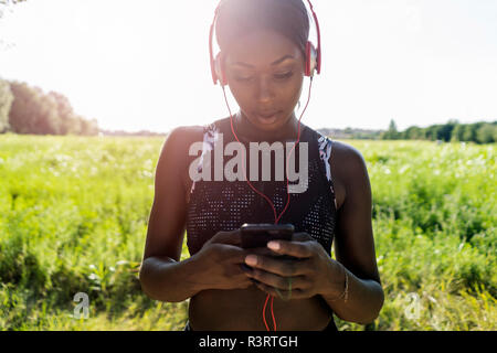 Junge Athlet in der Natur, Musik hören mit Kopfhörern, Smartphone Stockfoto