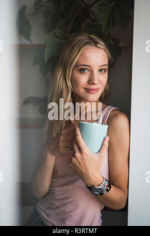 Portrait von lächelnden blonde junge Frau mit Coffee Mug Stockfoto