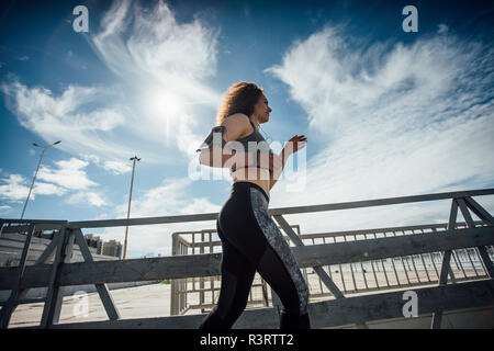 Junge athletische Frau läuft auf einem Pier Stockfoto