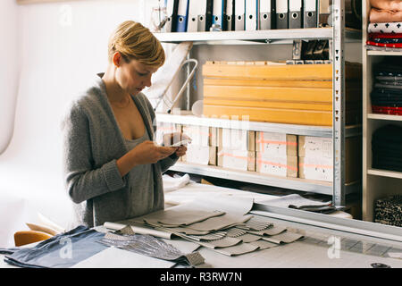 Fashion Designer über Handy in Studio Stockfoto