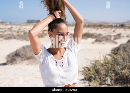 Junge Frau ihr Haar binden, Lachen Stockfoto