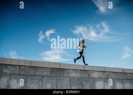 Junge athletische Frau läuft an einer Wand Stockfoto