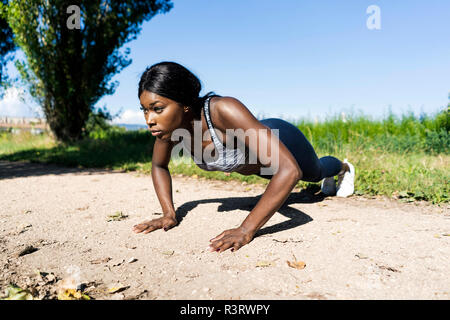 Junge Sportler tun Push-ups auf dem Feldweg Stockfoto