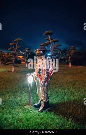 Spaceman stehend an eine Lampe in einem Park bei Nacht Stockfoto