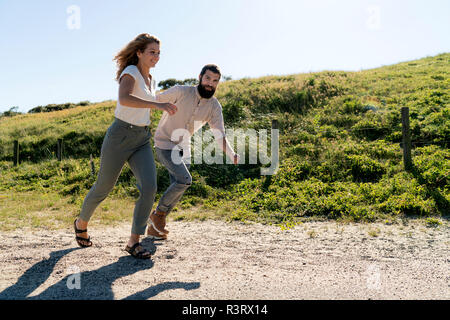 Ein junges Paar, das Spaß in den Dünen, laufen Hand in Hand Stockfoto