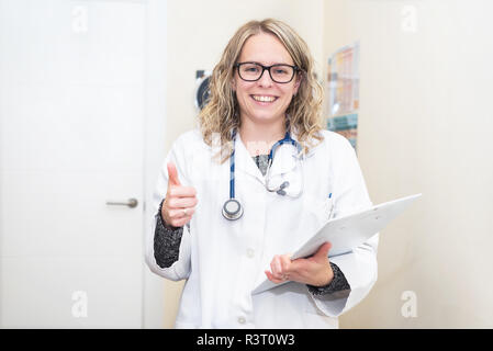 Portrait einer jungen Ärztin, die Daumen oben, positive Emotion. Stockfoto