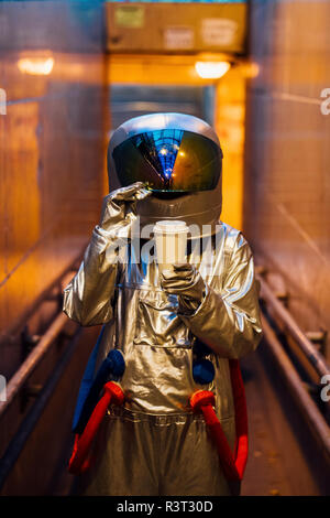 Spaceman in der Stadt bei Nacht mit Kaffee zum Mitnehmen in engen Durchgang Stockfoto