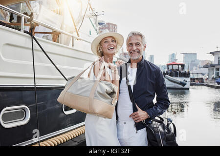 Alter Mann und junge Frau, die mit dem reisen Beutel auf Steg neben Yachtcharter Stockfoto