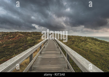 Deutschland, Schleswig-Holstein, Sylt, Wenningstedt, Promenade zum Strand unter Regen Wolken Stockfoto