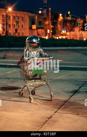 Spaceman in der Stadt in der Nacht auf Parkplatz innen Warenkorb Stockfoto