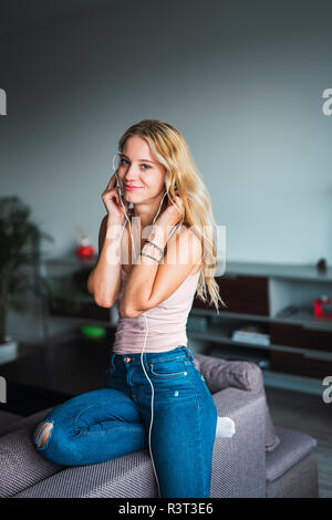 Portrait von lächelnden jungen Frau zu Musik über Kopfhörer zu Hause Stockfoto