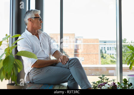 Nachdenklich reifer Mann am Fenster zu Hause sitzen Stockfoto