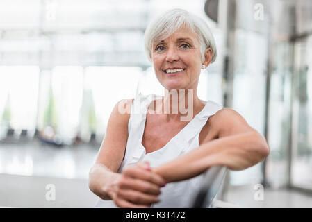 Portrait von lächelnden älteren Frau sitzt im Wartebereich Stockfoto