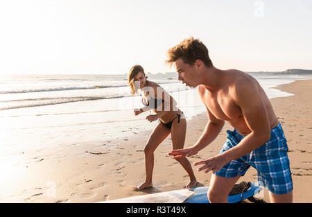 Junger Mann, junge Frau wie Sie surfen am Strand Stockfoto