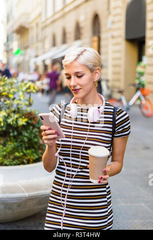 Porträt der jungen Frau mit gestreiftem Kleid stehen auf der Straße mit Kaffee zu gehen, Zelle Telefon Stockfoto