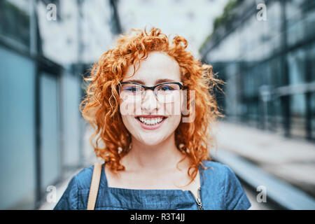 Portrait einer jungen rothaarigen Frau mit Brille, lächelnd Stockfoto