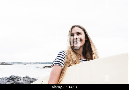 Junge Frau am Strand Surfbrett, Porträt Stockfoto